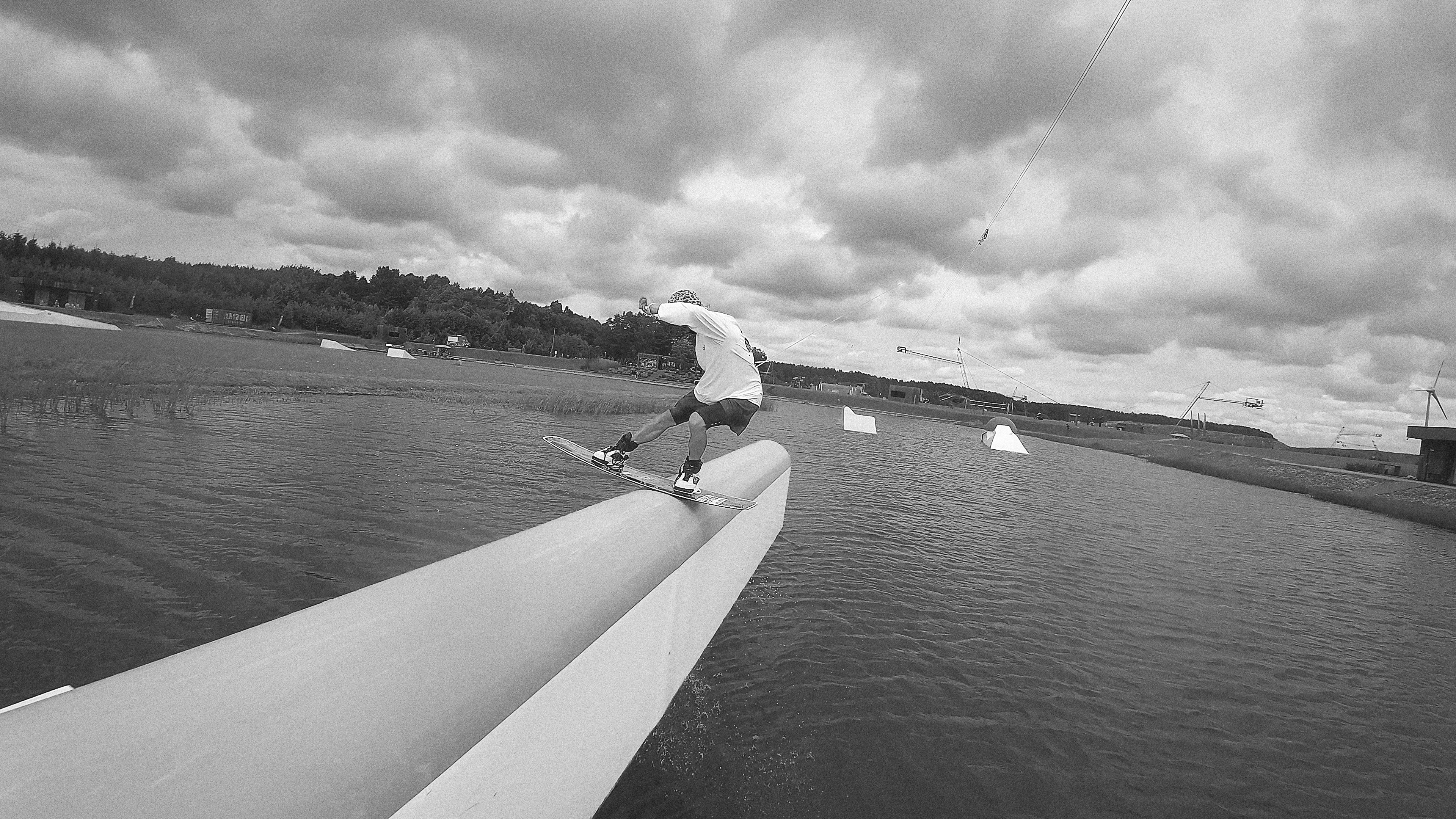 A rider crossing the cable line under heavy cloud, grey water below.