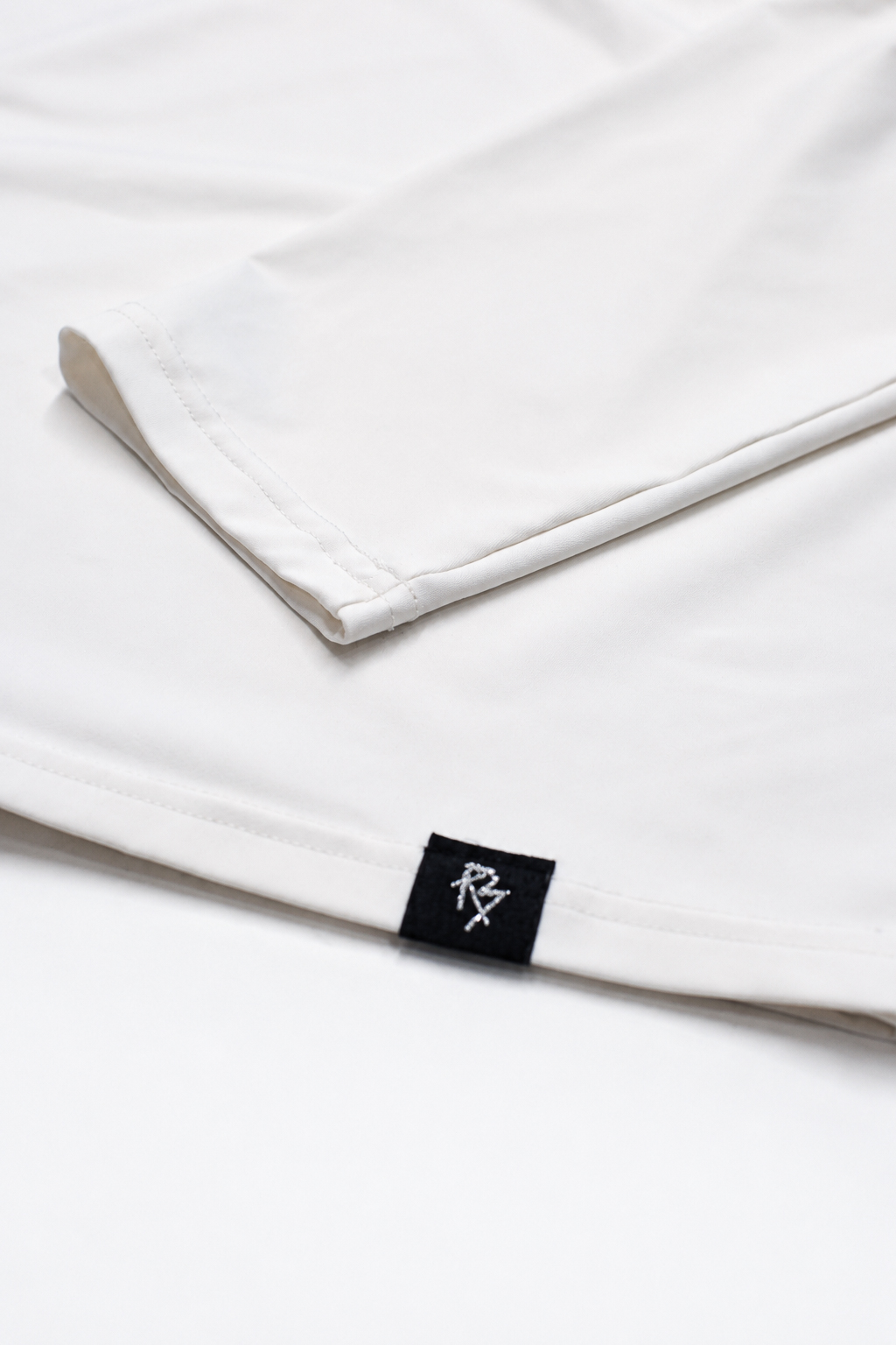 Close on the sleeve of the white rash guard, with the cuff and sleeve graphic visible.